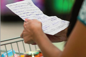 Imagen de una consumidora, con un carrito Mercadona, mirando la lista de la compra. Mercadona es asocaido de AINIA